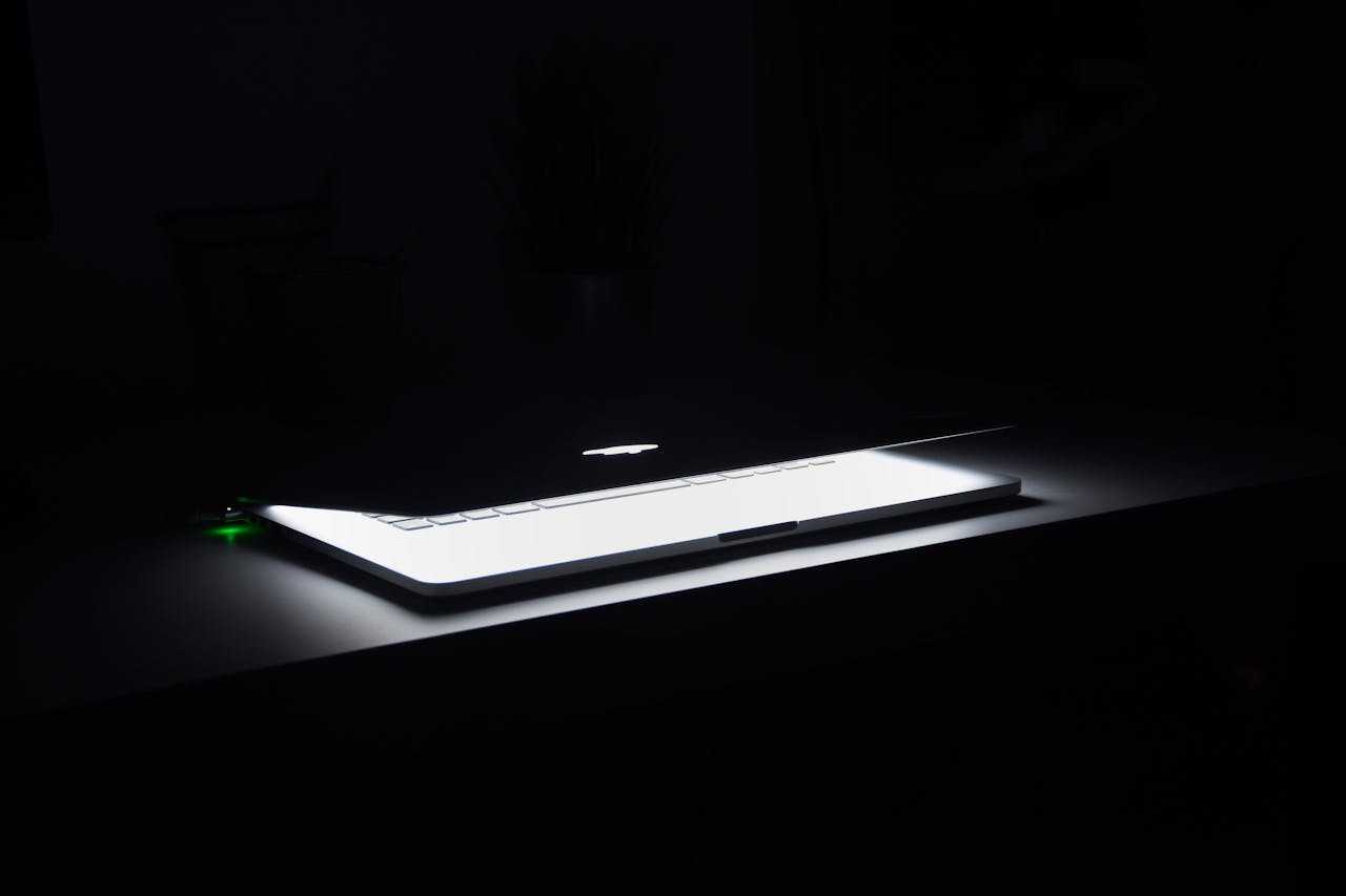 services-02 A dramatic, low-light image of a slightly open laptop with glowing keys on a dark desk.